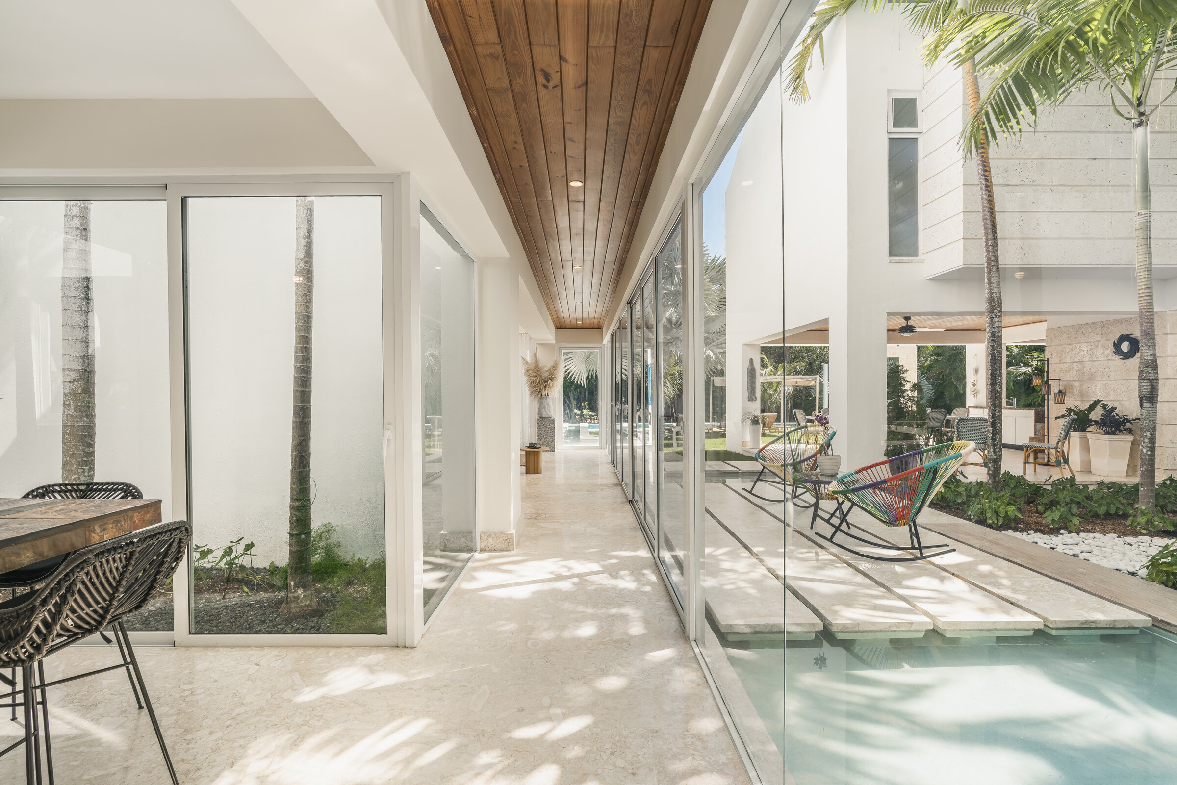 Corredor cubierto Villa Eden — sillas mecedoras con vista a piscina interior