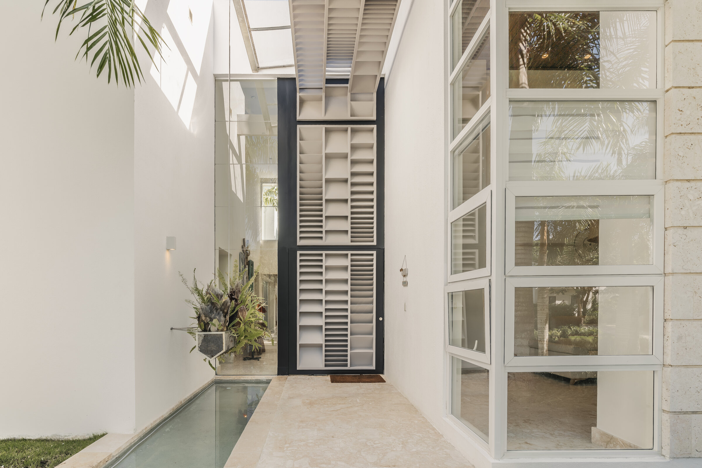 Vestíbulo de entrada Villa Eden — acceso interior privado con espejo de agua