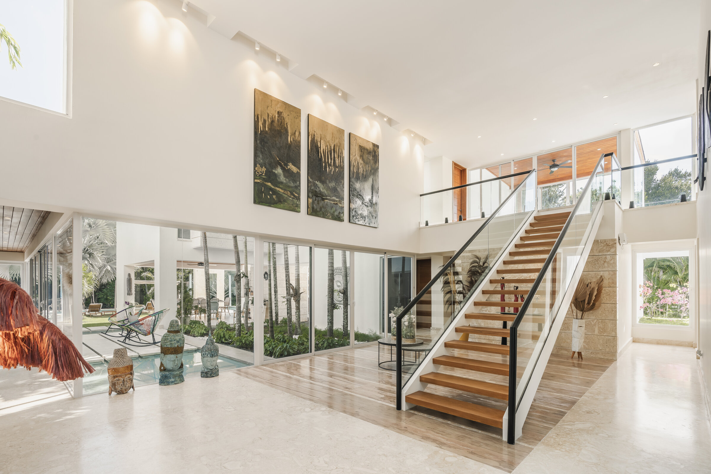 Hall principal Villa Eden — doble altura con arte, escaleras flotantes y patio