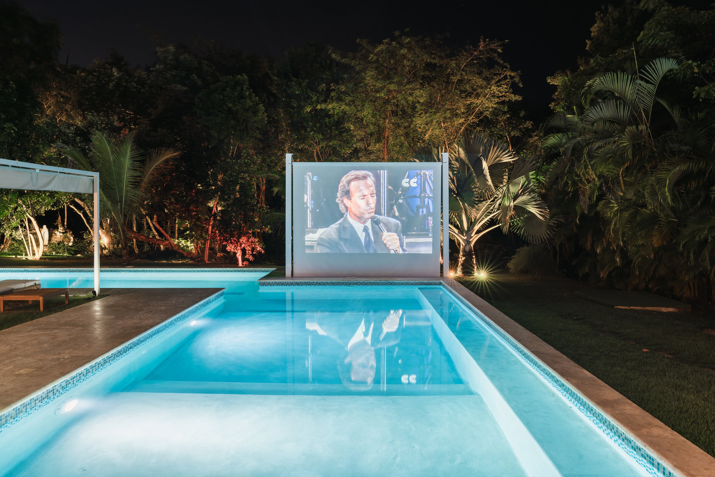 Cine al aire libre Villa Eden — pantalla junto a la piscina iluminada de noche