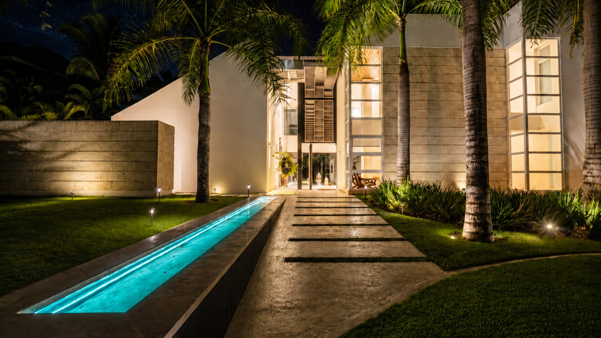 Fachada de Villa Eden de noche — entrada iluminada junto a la piscina